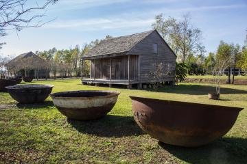 A few large bowls and an old cabin at the Whitney plantation during a whitney plantation tour