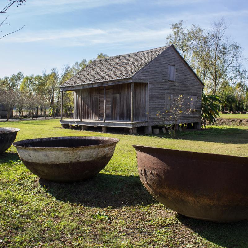 A few large bowls and an old cabin at the Whitney plantation during a whitney plantation tour