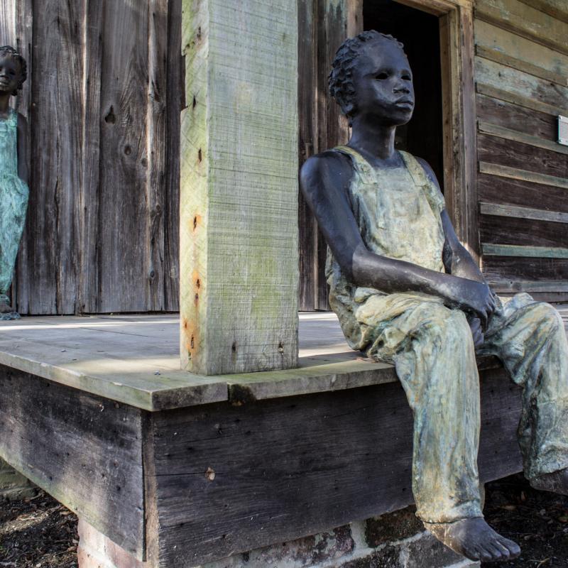 statue of boy sitting on porch at Whitney plantation