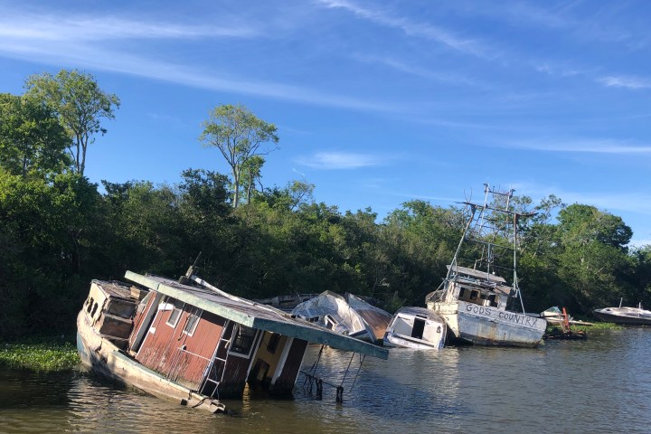 a boat floating along a river next to a body of water
