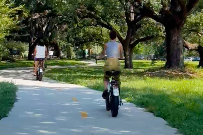 a man riding a motorcycle down a street next to a tree